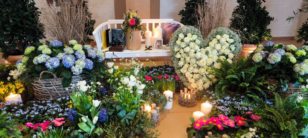 Blumenarrangement mit Rosenherz, Fotos und Kerzen bei einer Lebensfeier