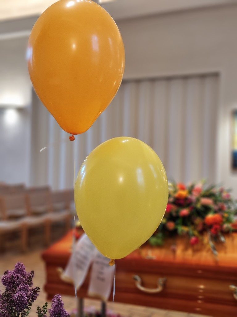 Bunte Luftballons am Sarg bei einer Lebensfeier