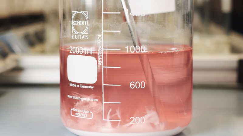 Laborgefäß mit rötlicher Lösung bei der Extraktion der Elemente