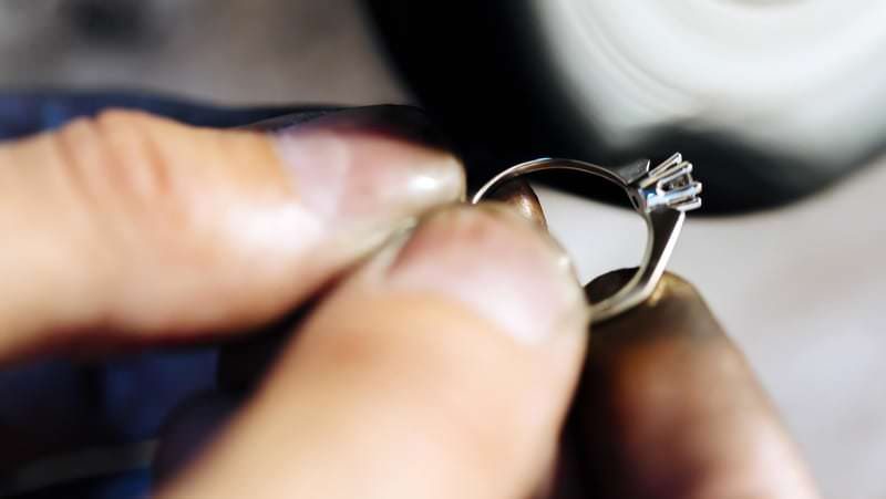Goldschmied fasst einen Edelstein in einen Ring